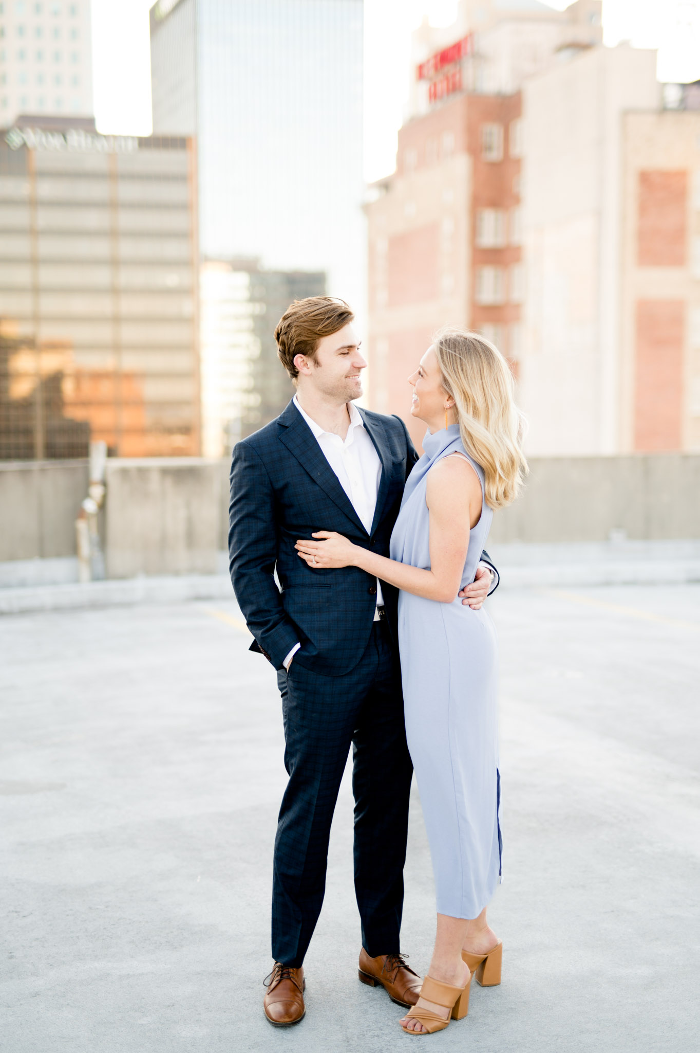 Couple smile at each other on city rooftop.