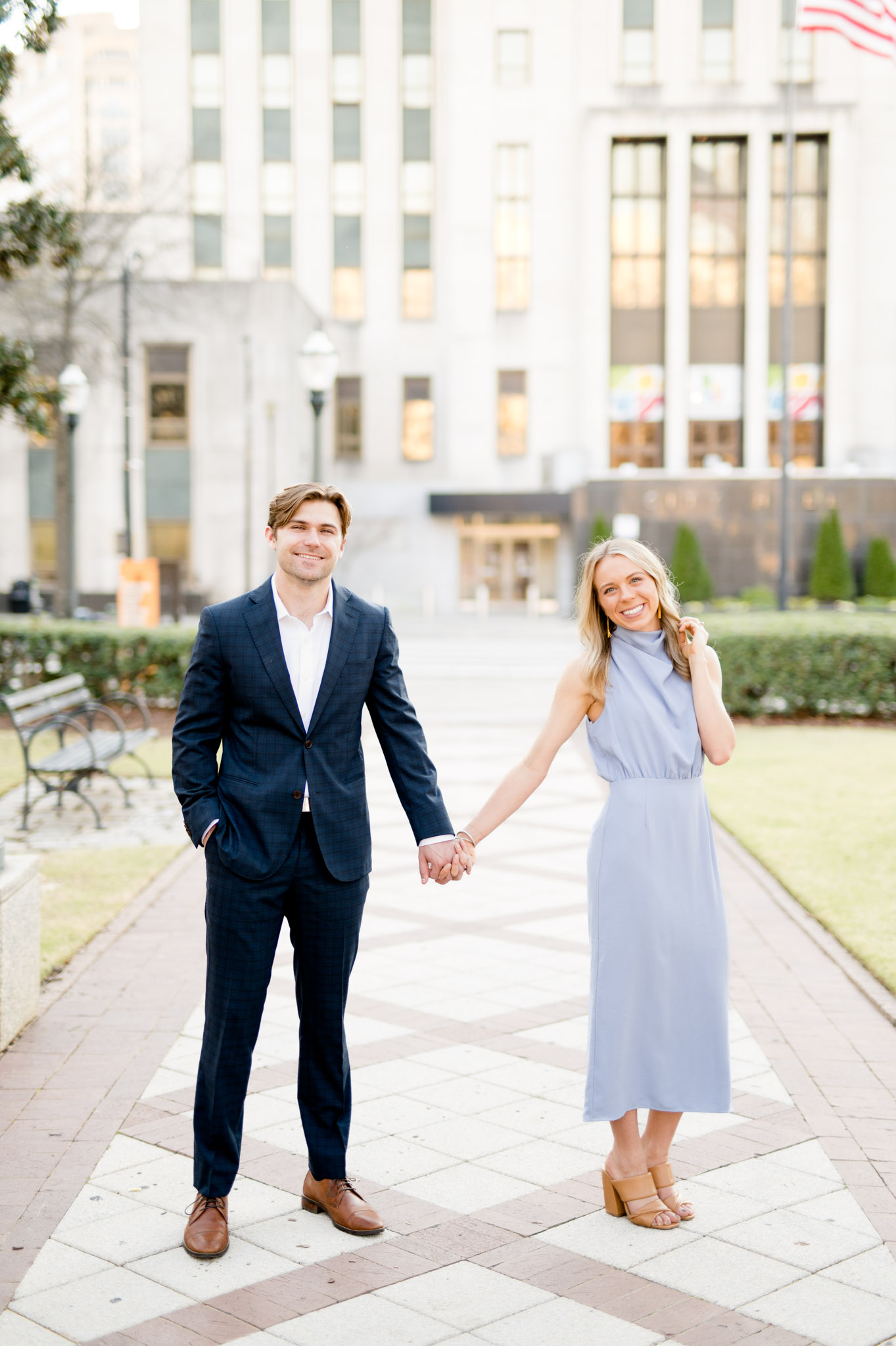 Couple stands in downtown and smiles at camera.