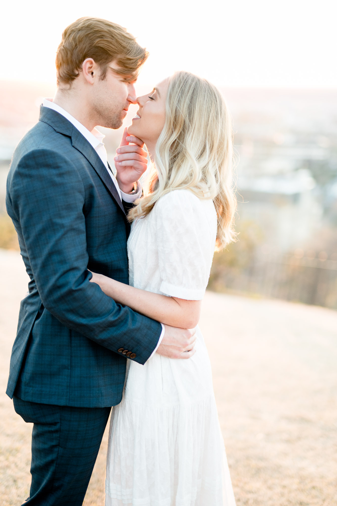 Groom pulls fiance in by chin for kiss.