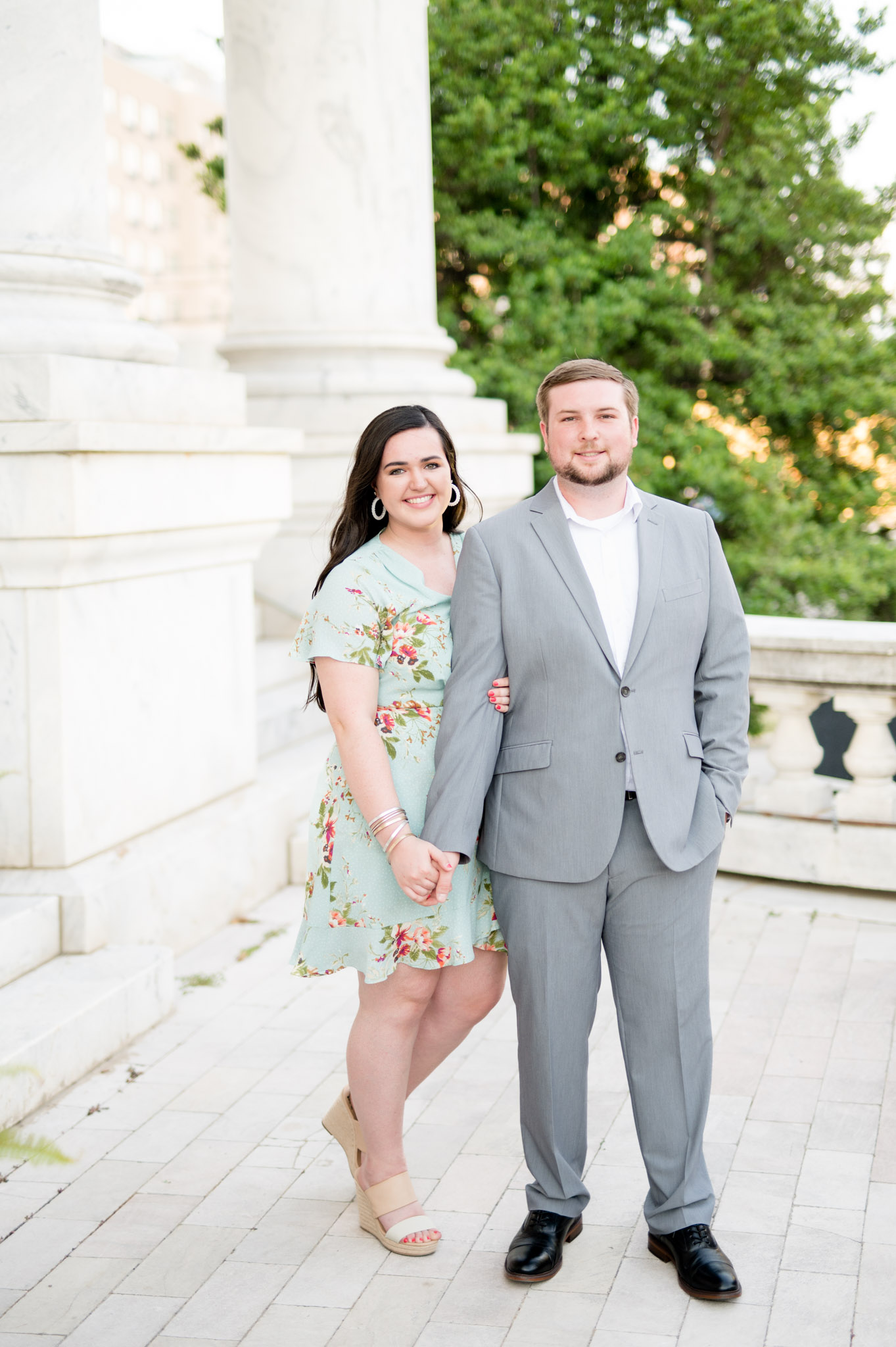 Couple smiles towards camera while holding hands.