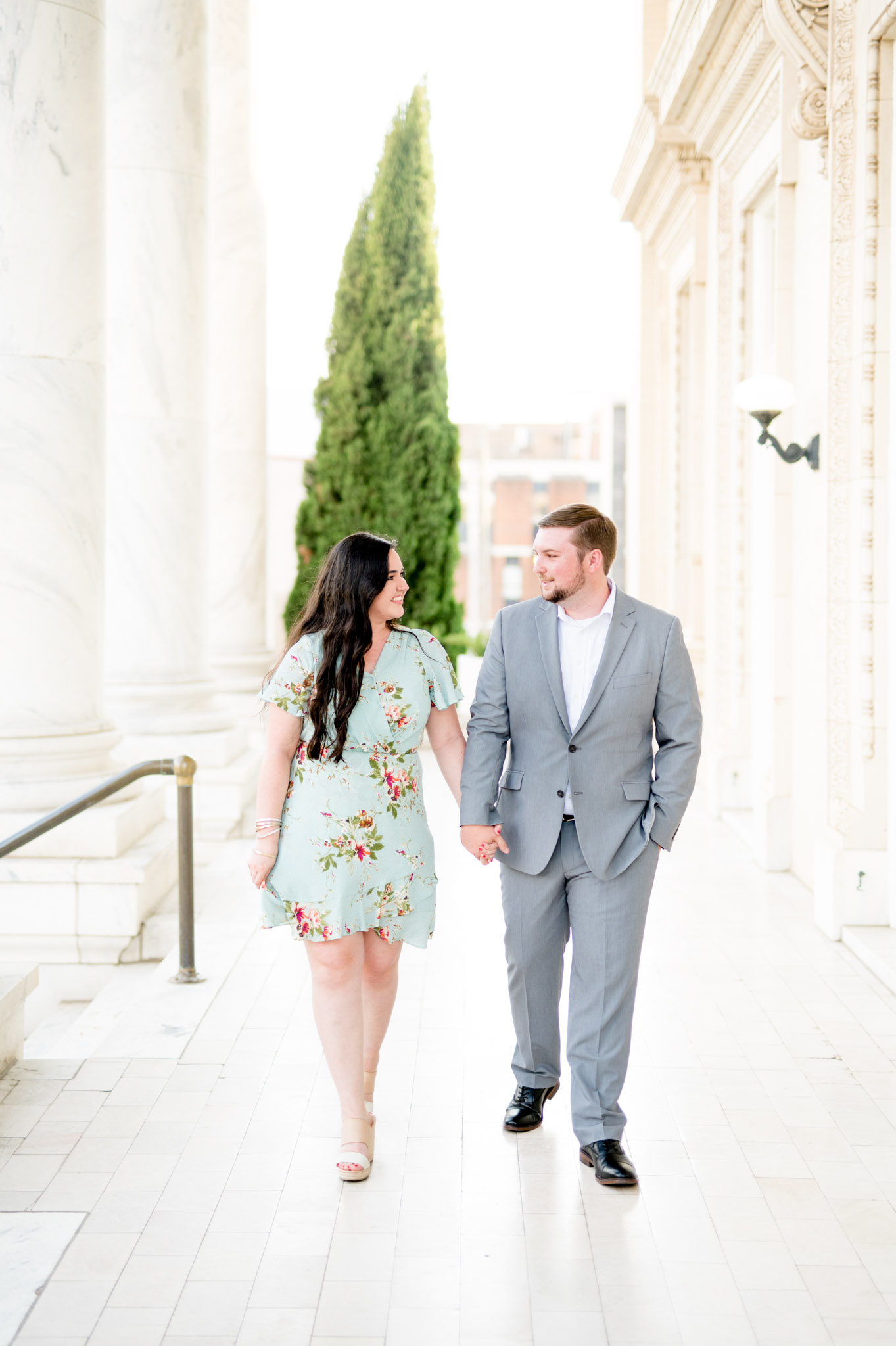 Couple walks down marble walkway.