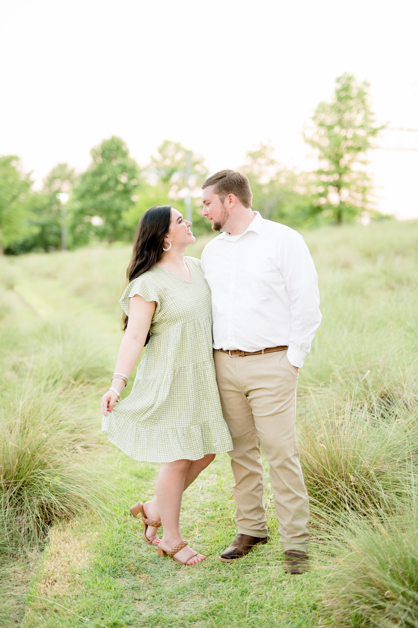 Couple looks and smiles at each other in field.