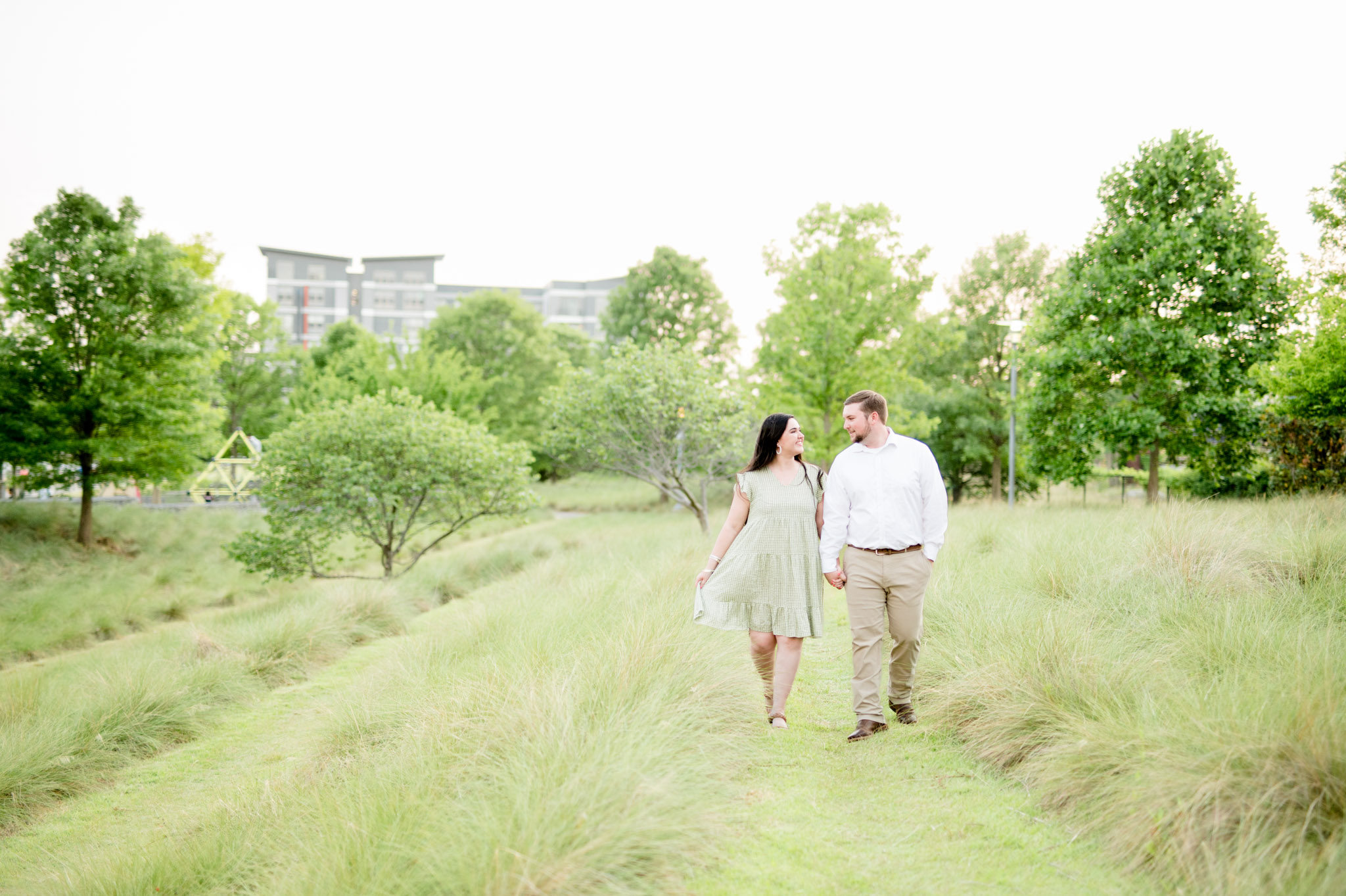 Couple walks through grassy field.