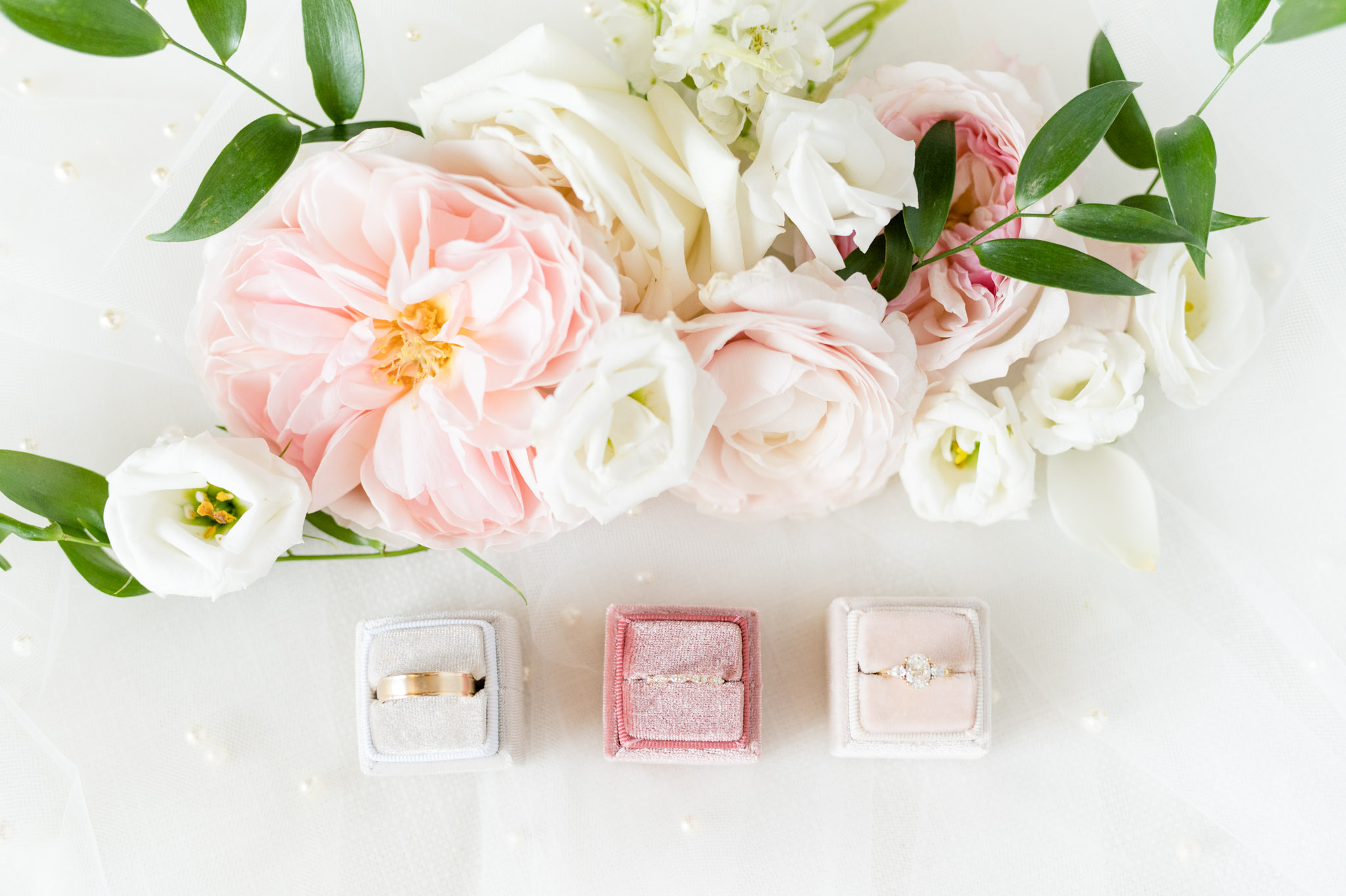 Wedding rings in velvet boxes with flowers surrounding them.