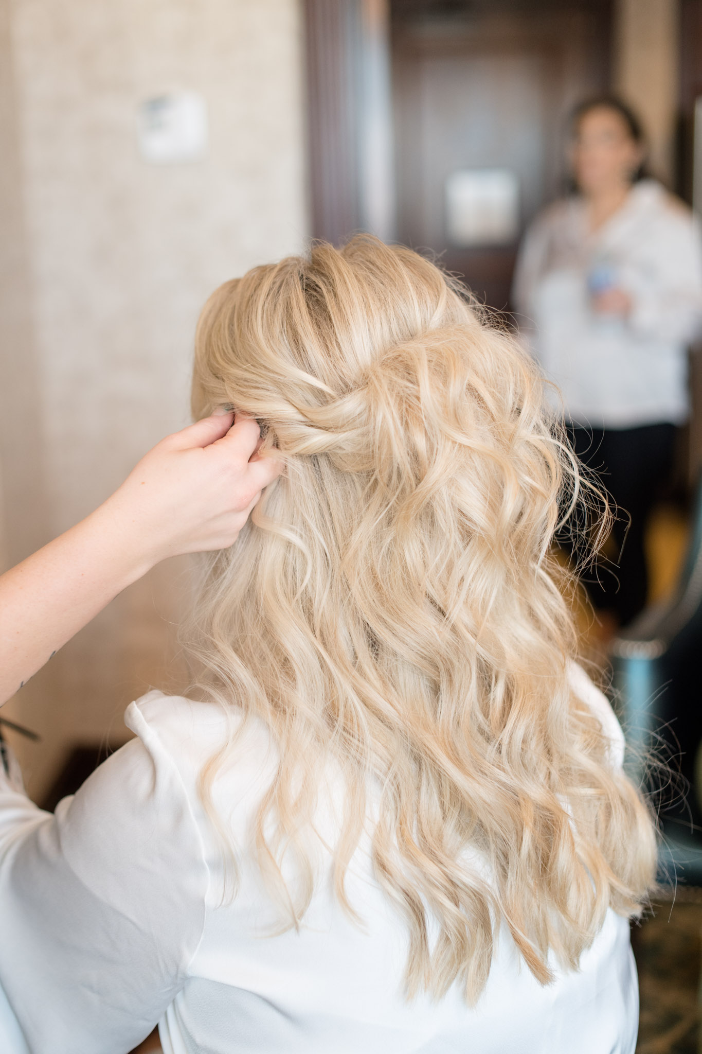 Hair artist finishes bride's hair.
