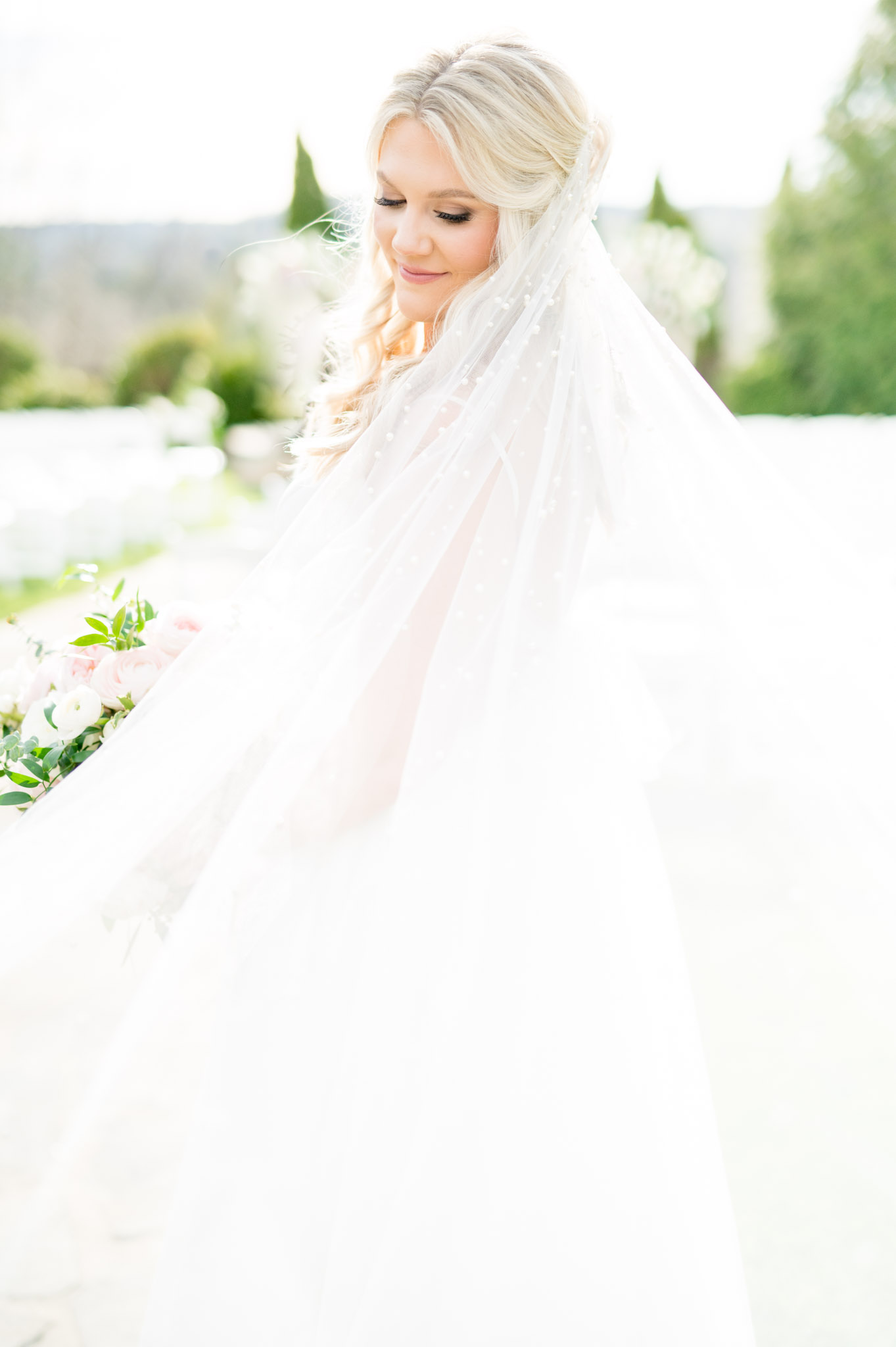 Bride looks over shoulder as veil blows in wind.