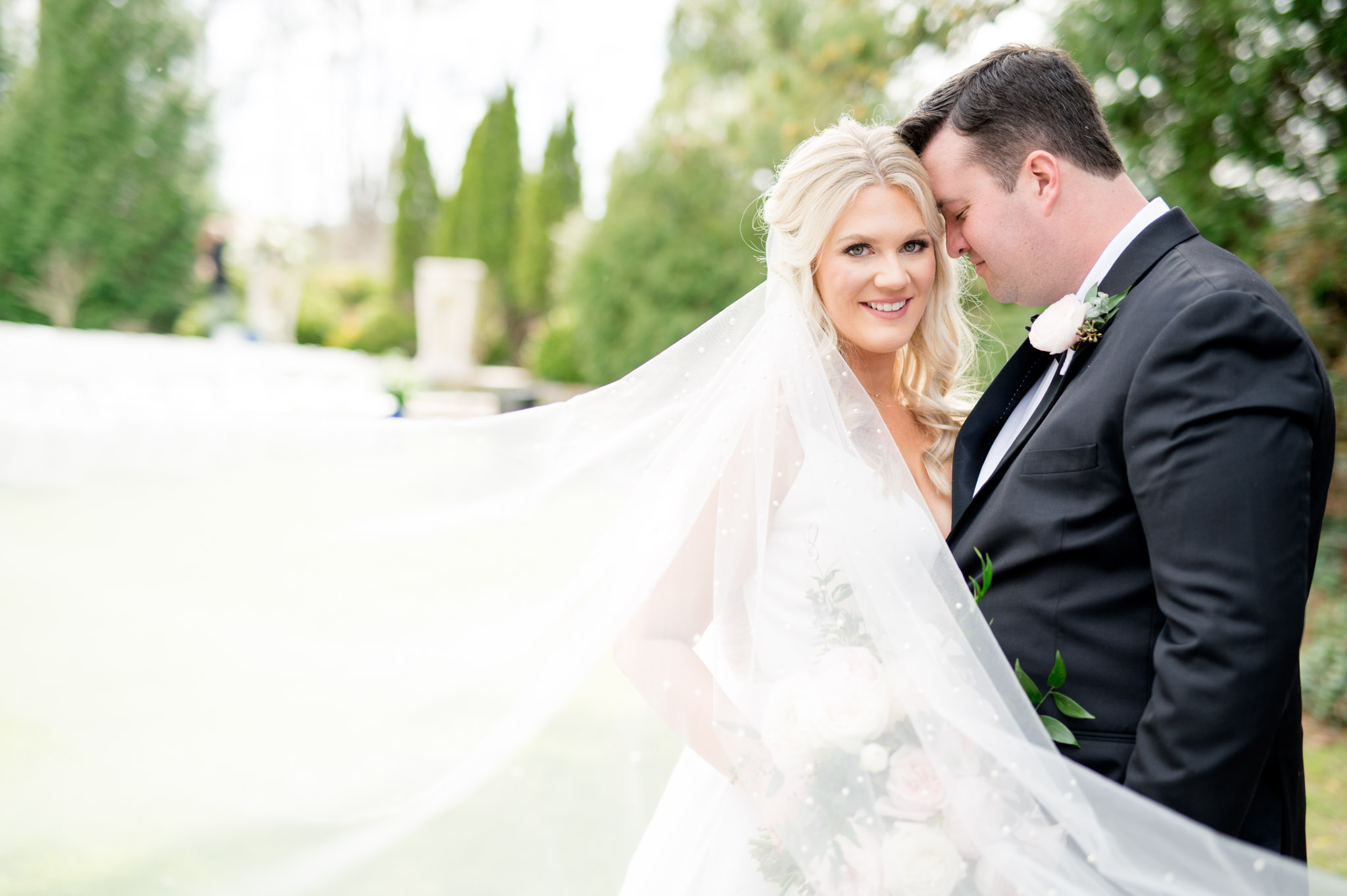 Bride smiles as groom snuggles in.