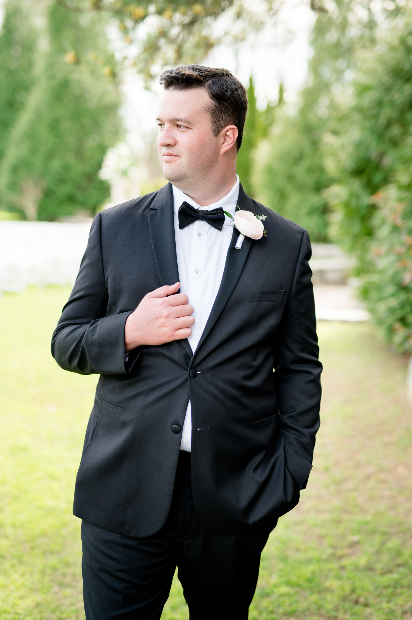 Groom holds lapel and looks over shoulder.