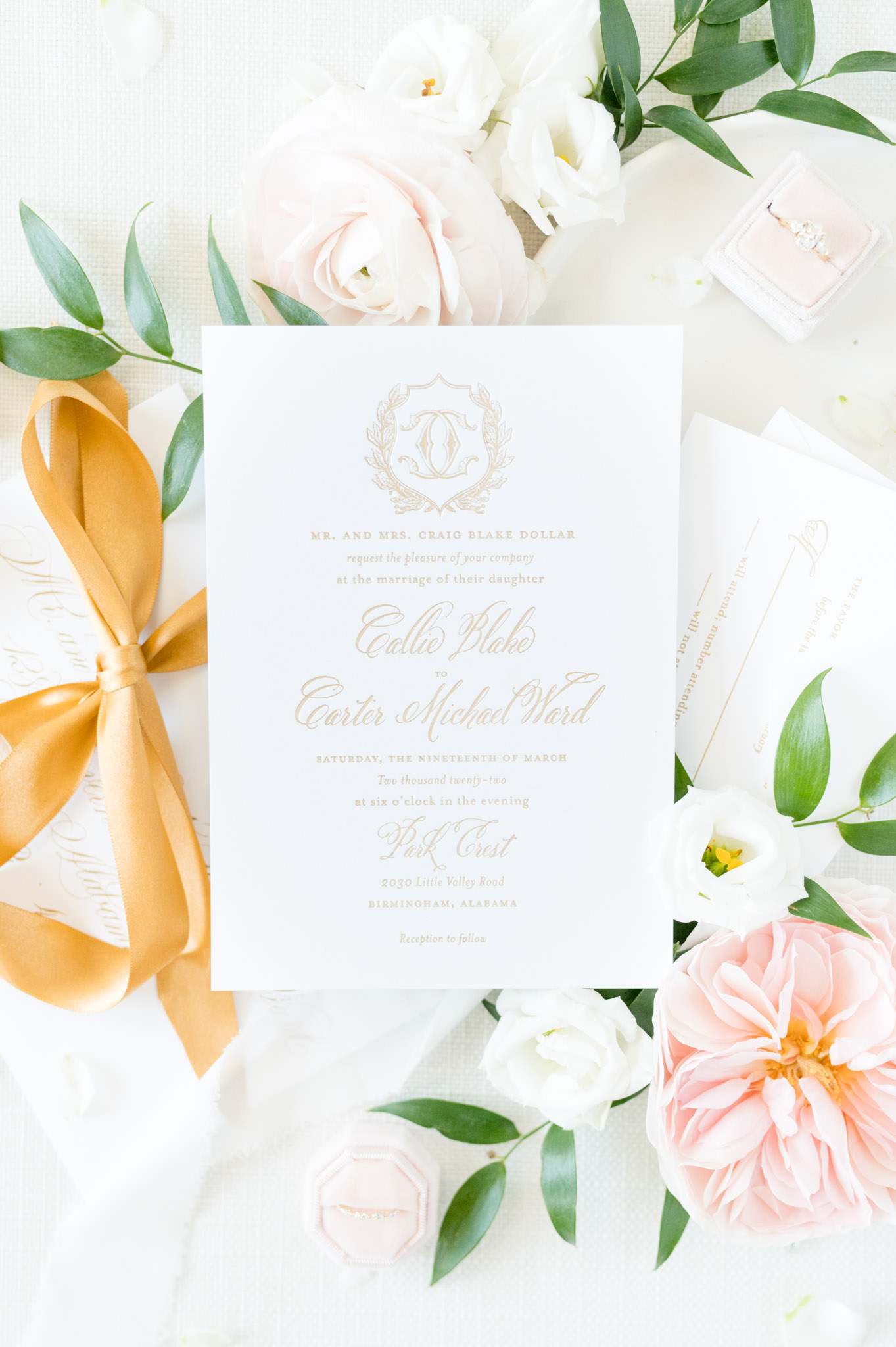 Wedding invitation sits with envelopes and flowers.