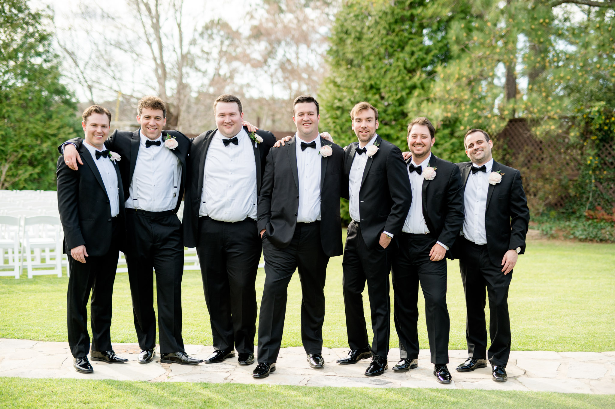 Groom and groomsmen put arms over shoulders.