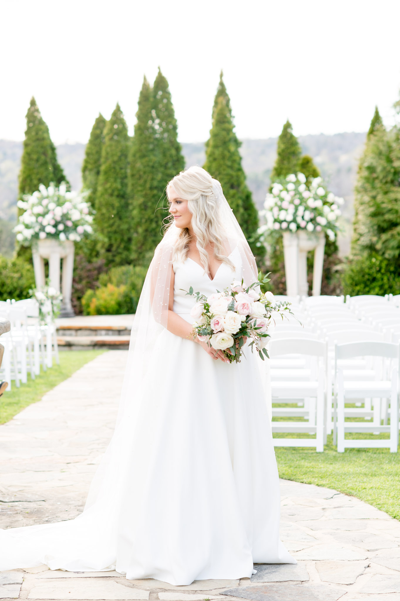 Bride holds flowers and looks over shoulder.