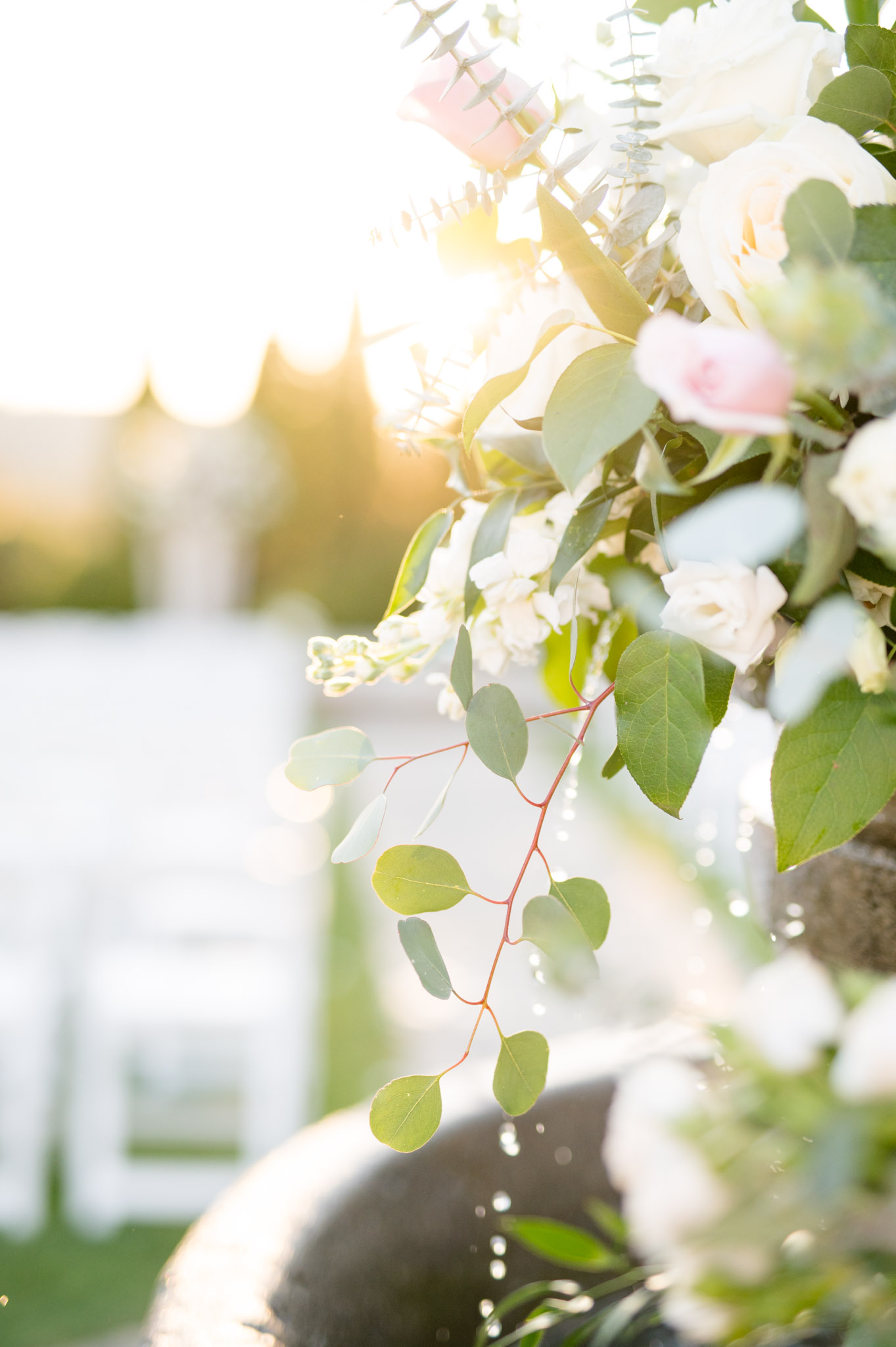 Flowers sit on fountain at wedding ceremony.