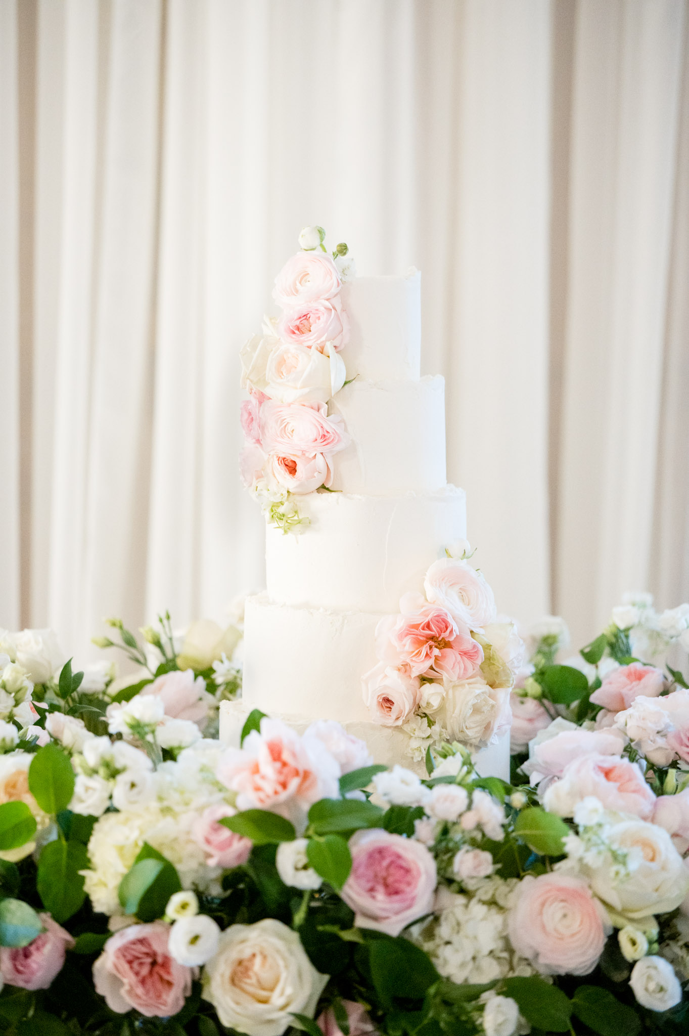 Wedding cake sits on table with flowers surrounding it.