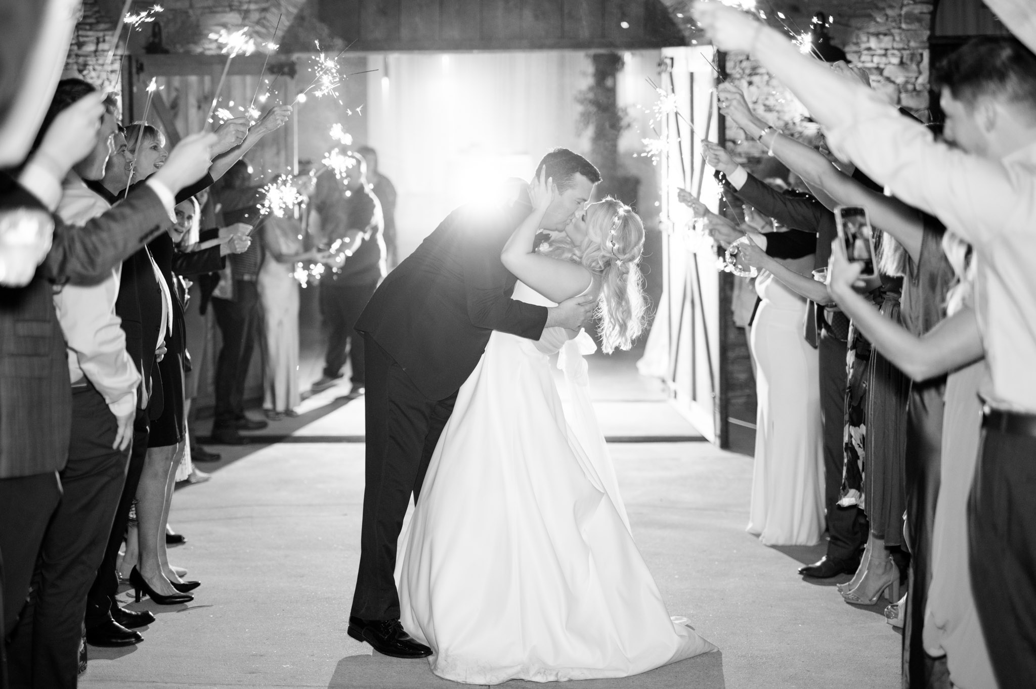 Bride and groom kiss under sparklers.